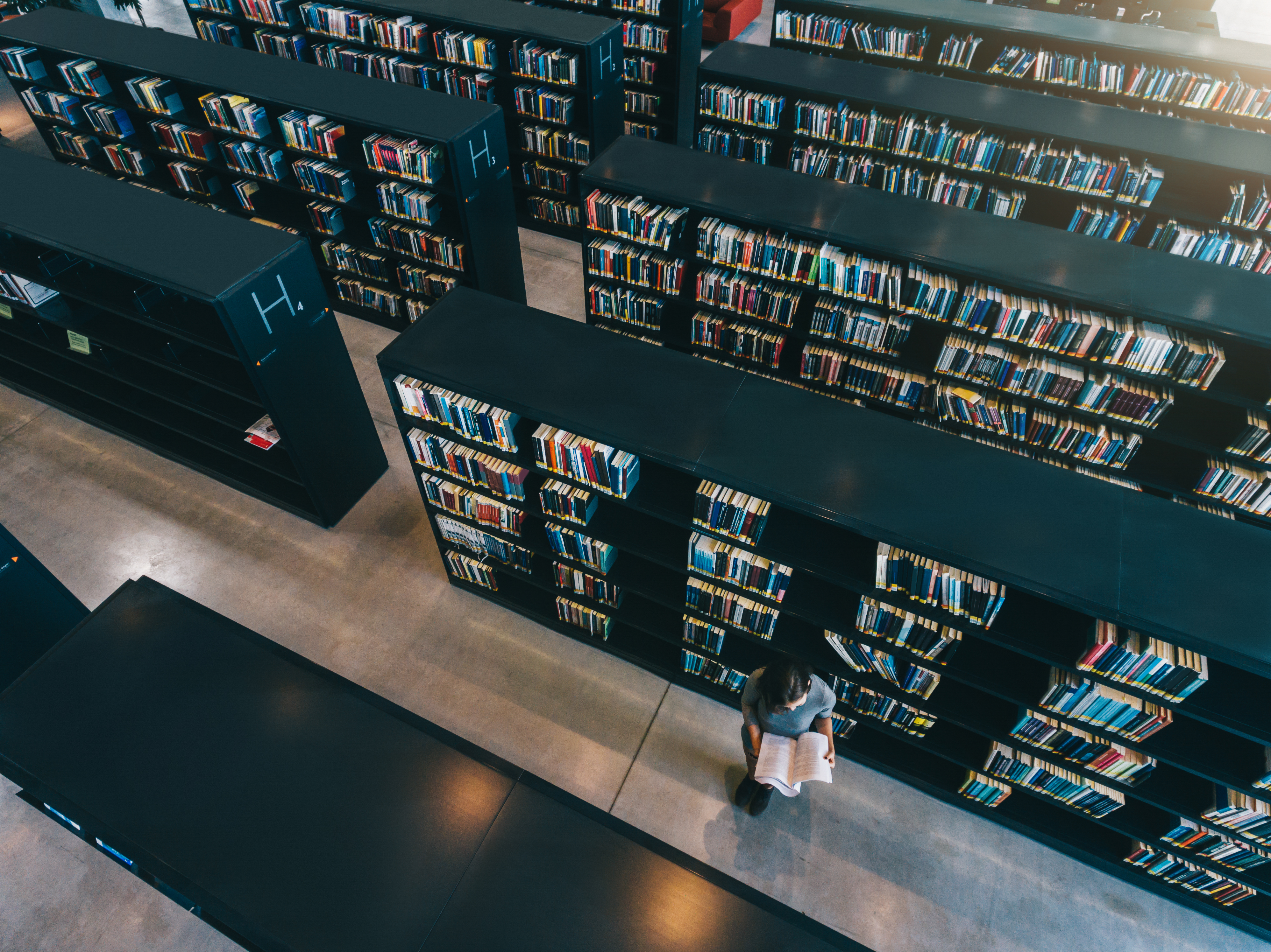 female-student-at-library-bookshelf-reading-book