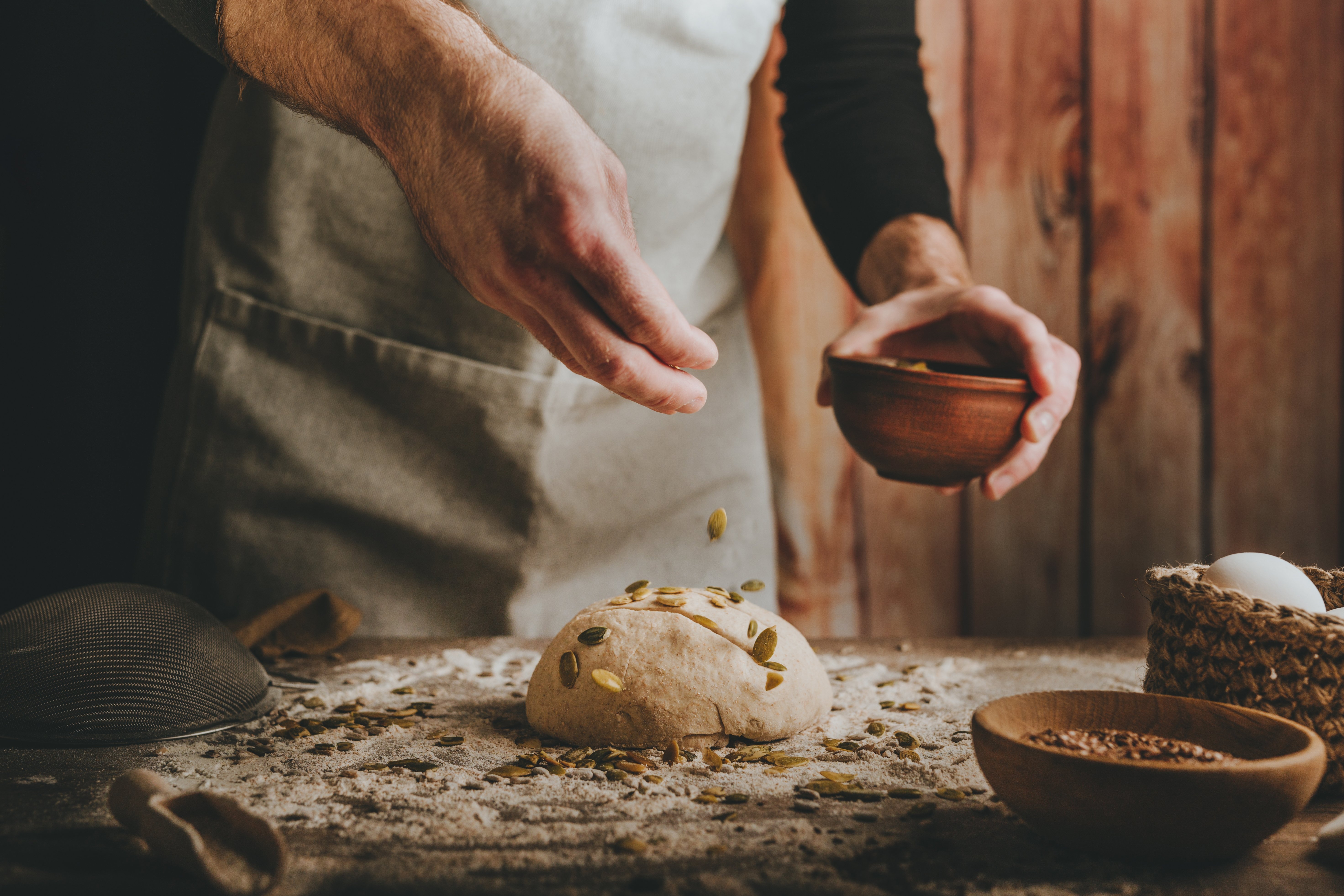 young-man-kneading-dough-on-dark-background